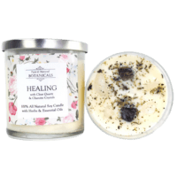 White candle in glass jar with crystals and herbs on top. Healing written on label