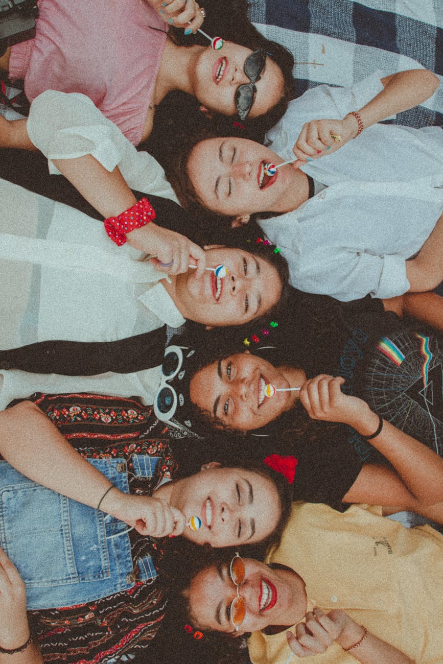 women lying down eating lollipop.  Social connection for social wellnes