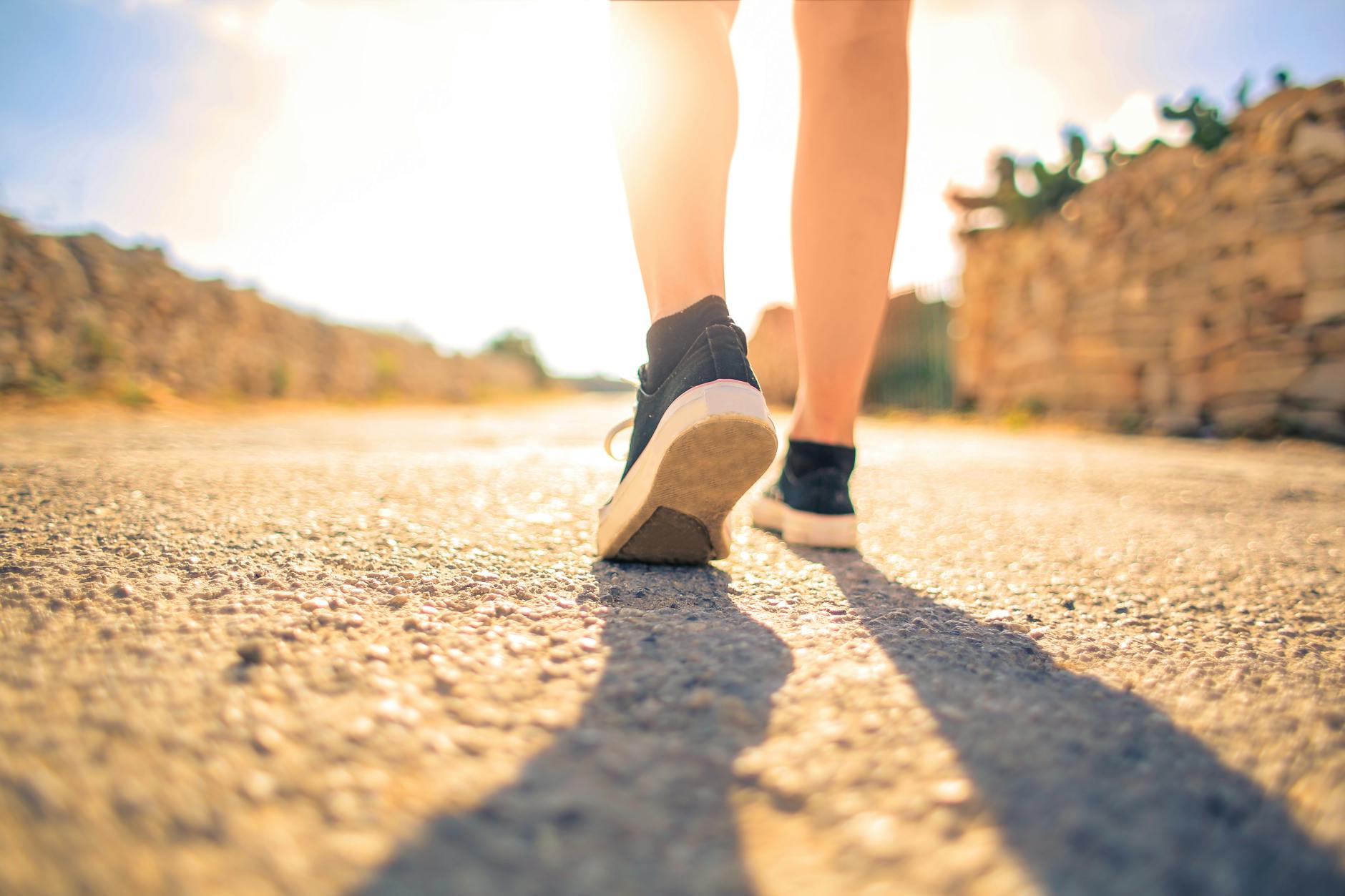 woman walking on pathway under the sun to get in physical activity