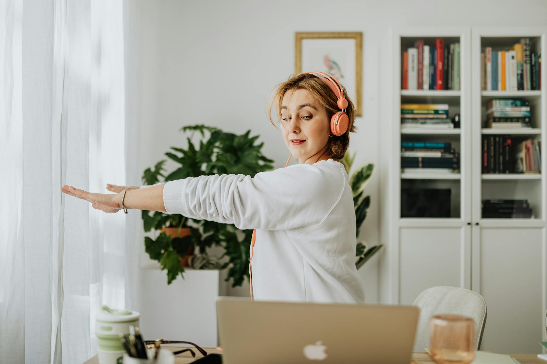 woman exercising with laptop and headphones to get physical wellness throughout day.