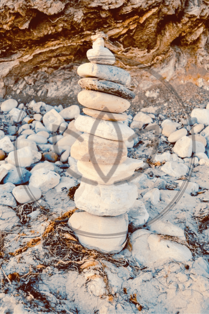 rocks stacked on beach with lotus flower overlay for spiritual wellness