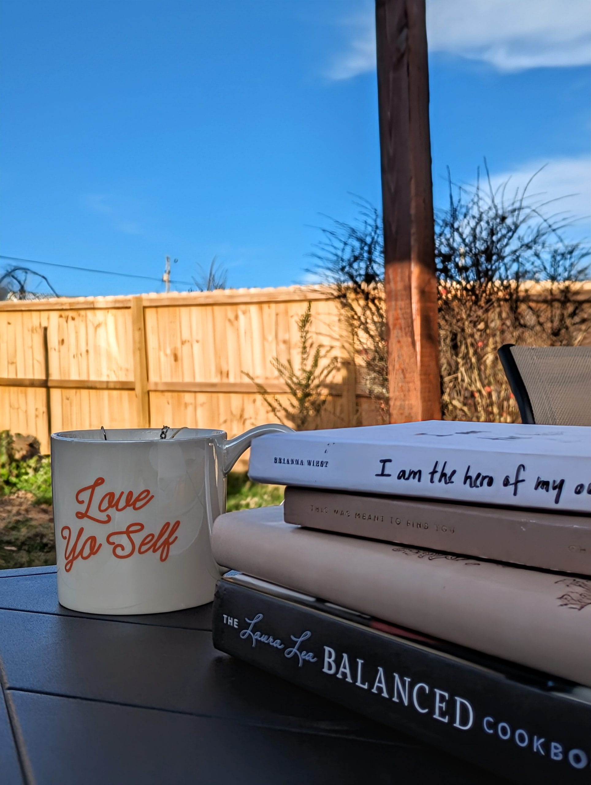 hormonal balance feature image. Stack of books on table outside next to a mug with blue sky in background
