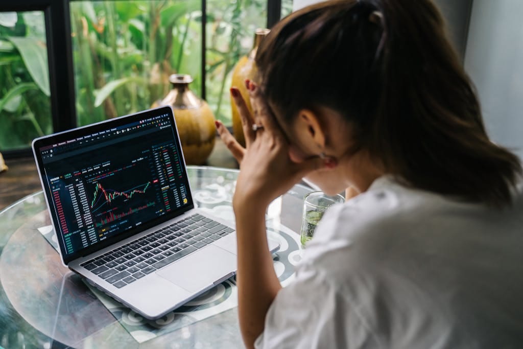 Woman Looking at Cryptocurrency Charts on Her Laptop, stressed about financial wellness