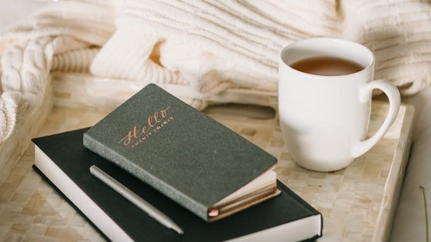 photo of cup beside book and journal